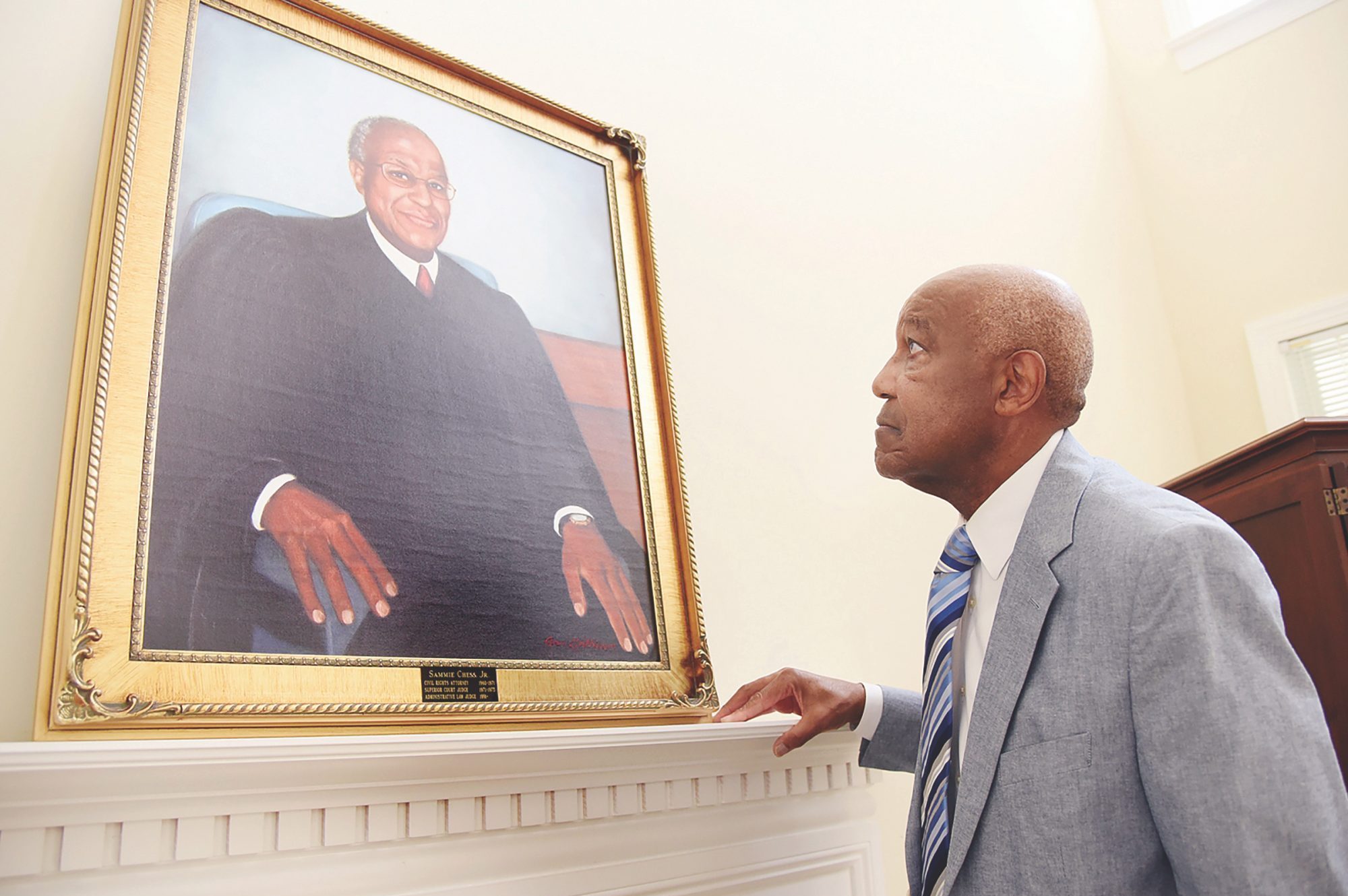 Retired Judge Sammie Chess, Jr., looks up at a painting of his portrait, a copy that hangs over the fireplace mantel at his home in Jamestown. The original painting is on display at the Guilford Country Courthouse in High Point.