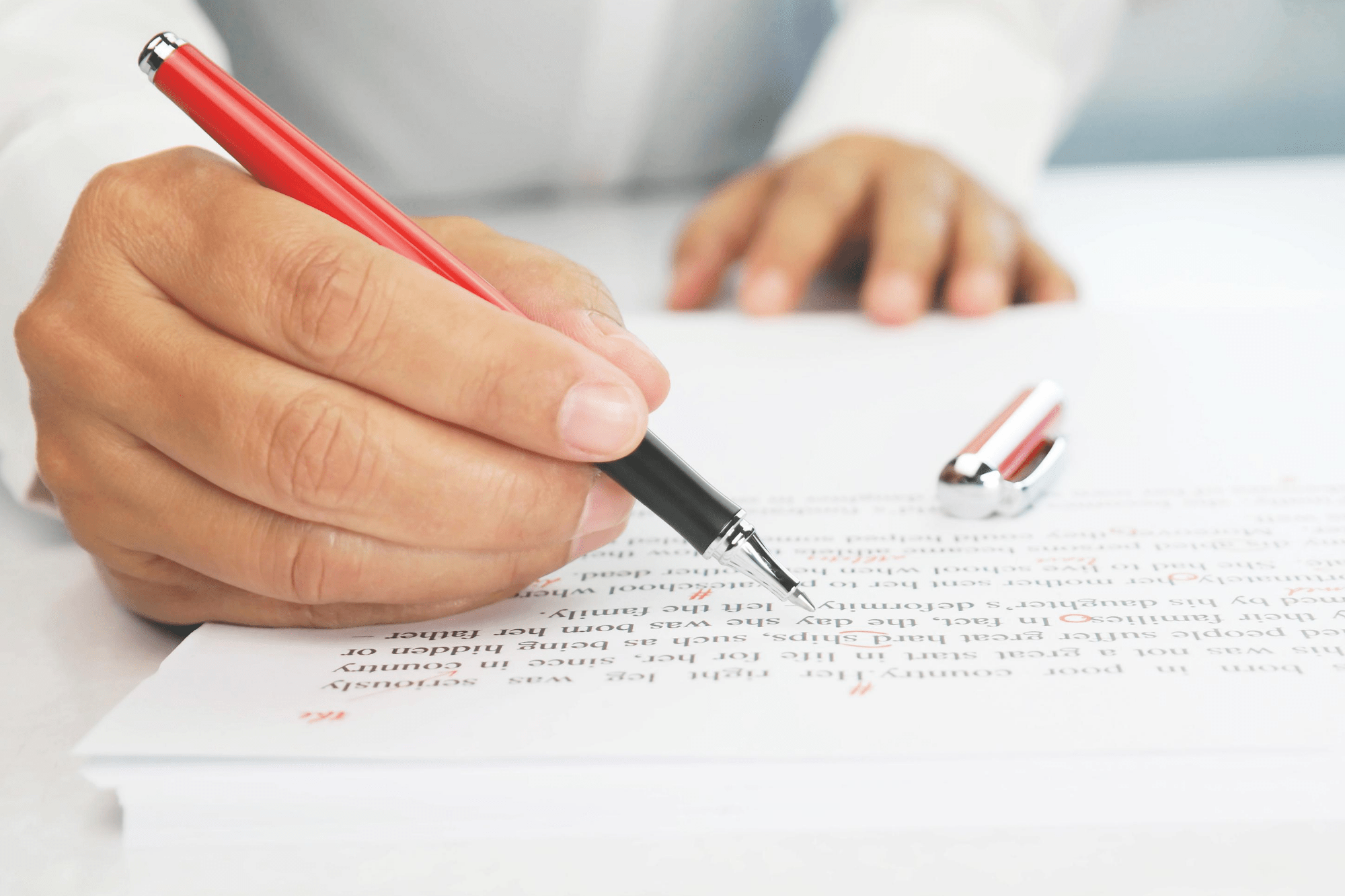 Person marking paper with red pen