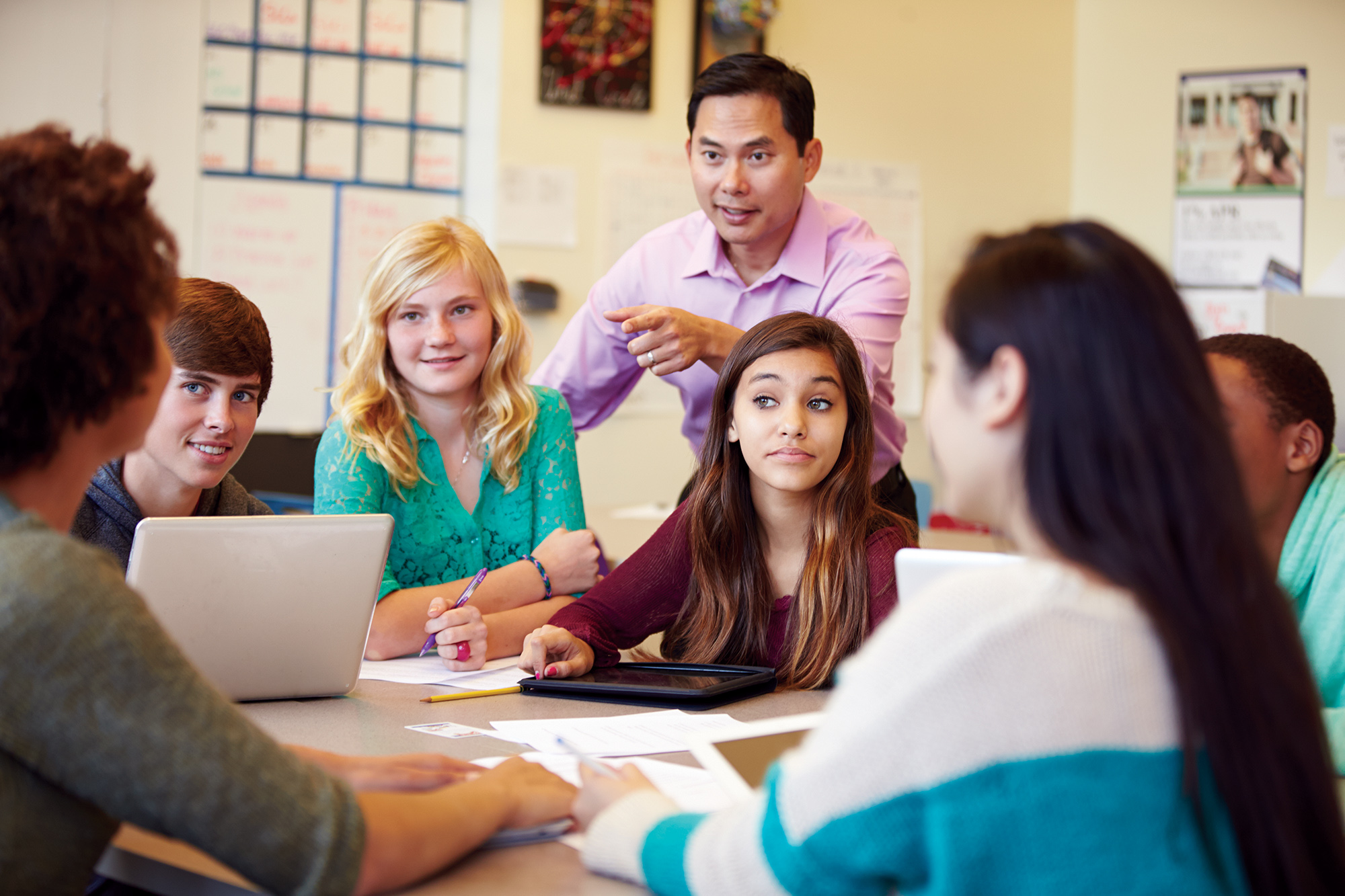 High School Students With Teacher In Class Using Laptops Smiling